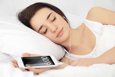 woman sleeping with earbuds and smartphone